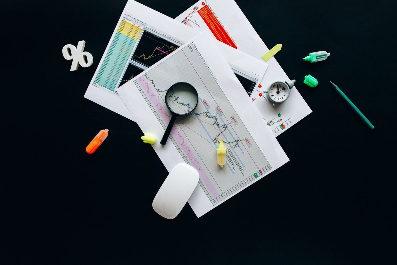 Mastering the First Impression: Your intriguing post title goes here Overhead view of an office desk with financial documents, a magnifying glass, and stationery items, suggesting business analysis.