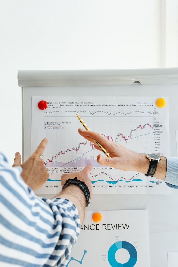 Offerings Two people analyzing financial charts on a whiteboard during a business meeting.