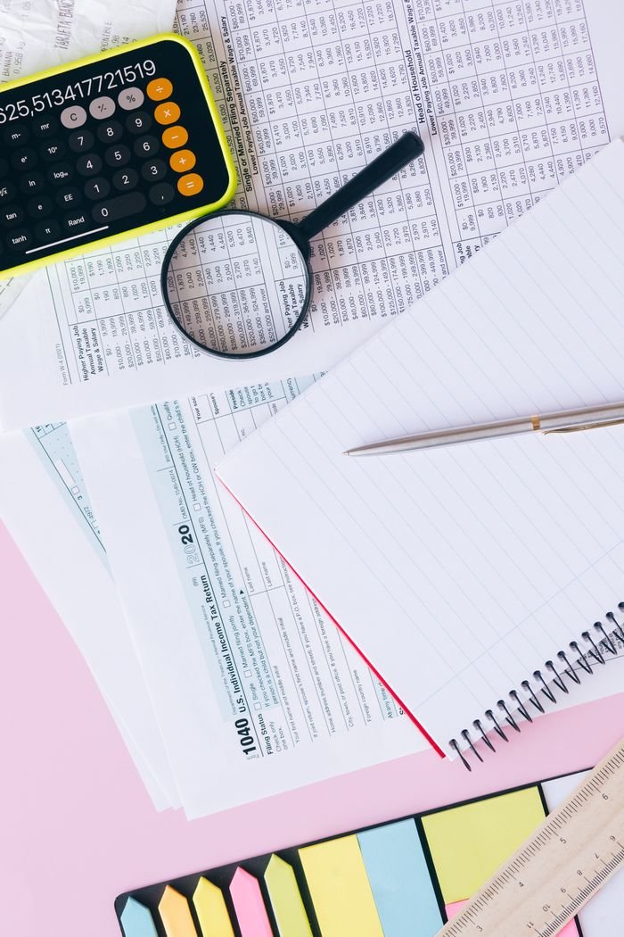 Crafting Captivating Headlines: Your awesome post title goes here Flat lay of financial documents, calculator, magnifying glass, and notebook on a pastel background.